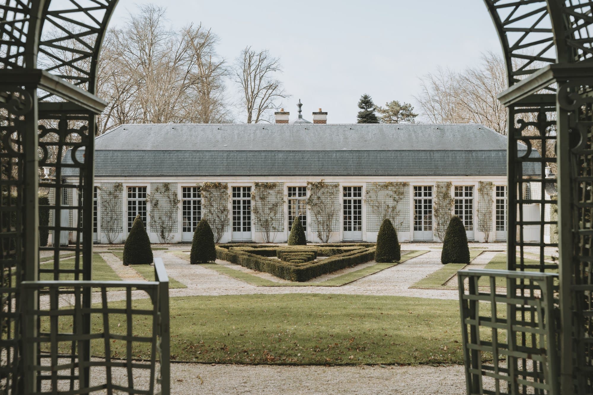 The orangery at Château de Chantilly, seen through the garden pergola